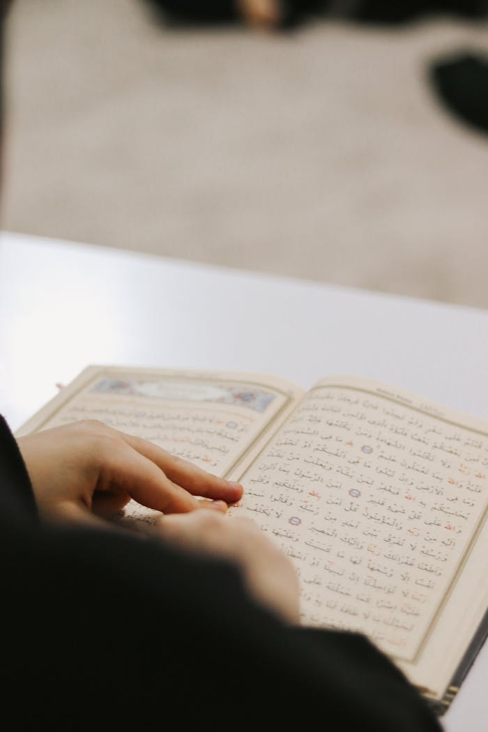 gallery-2 Hands peruse religious text, focusing on the Quran's pages.