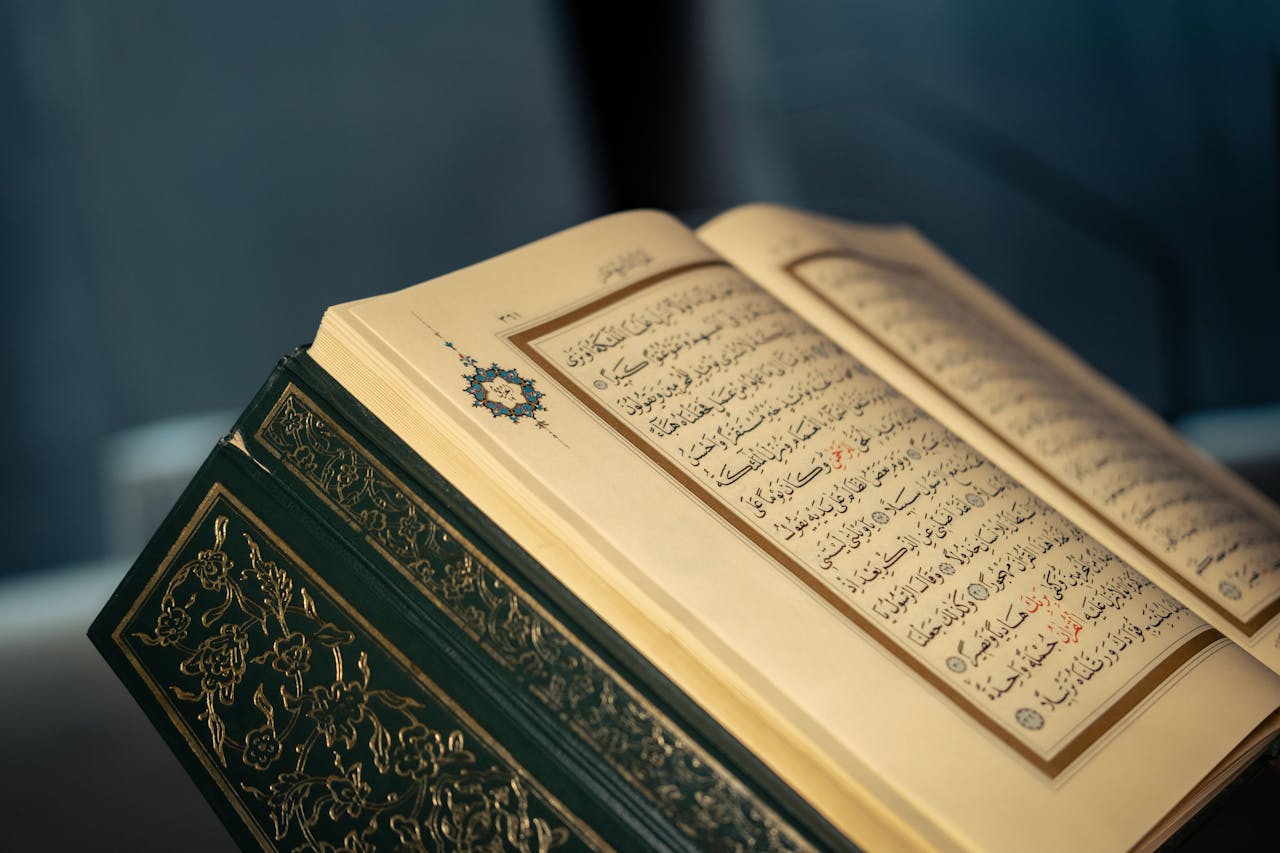 services-02 Close-up of an open Quran displaying intricate Arabic calligraphy on a page.