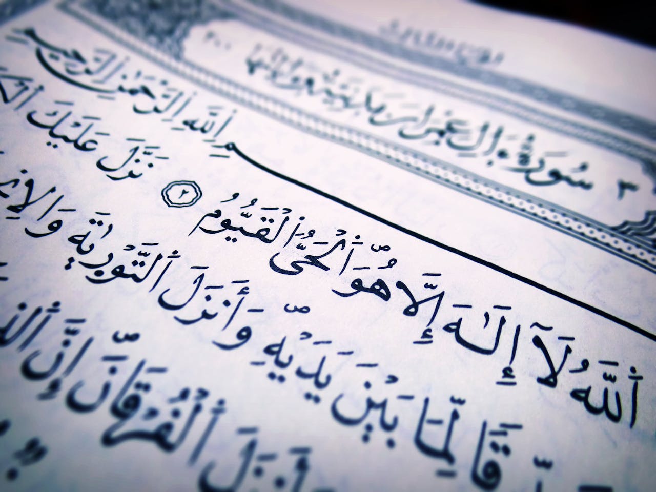 ours-journey Detailed close-up of Arabic script from a Quran page, highlighting religious text and calligraphy.