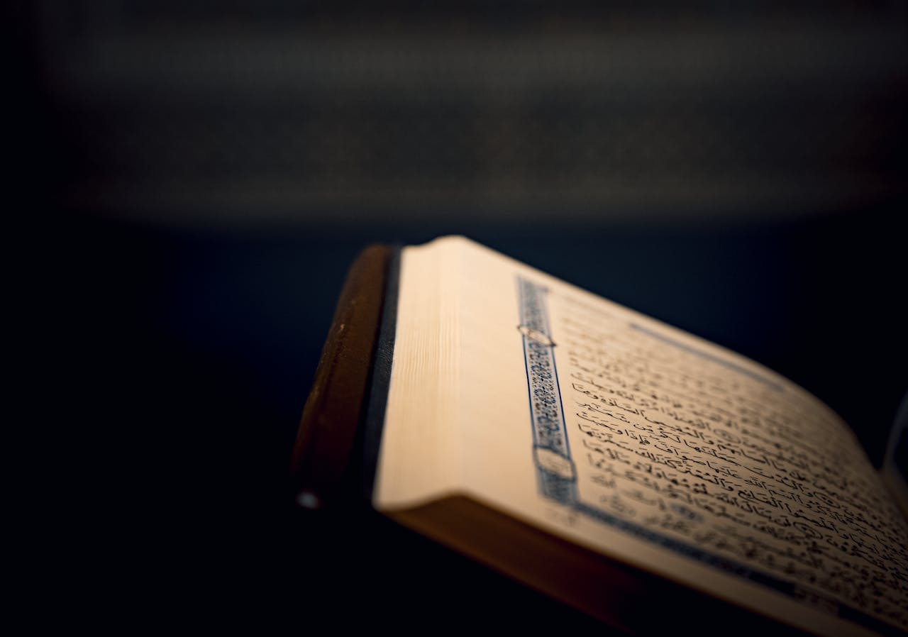 hero-img-02 Close-up of a Quran page with intricate Arabic script.